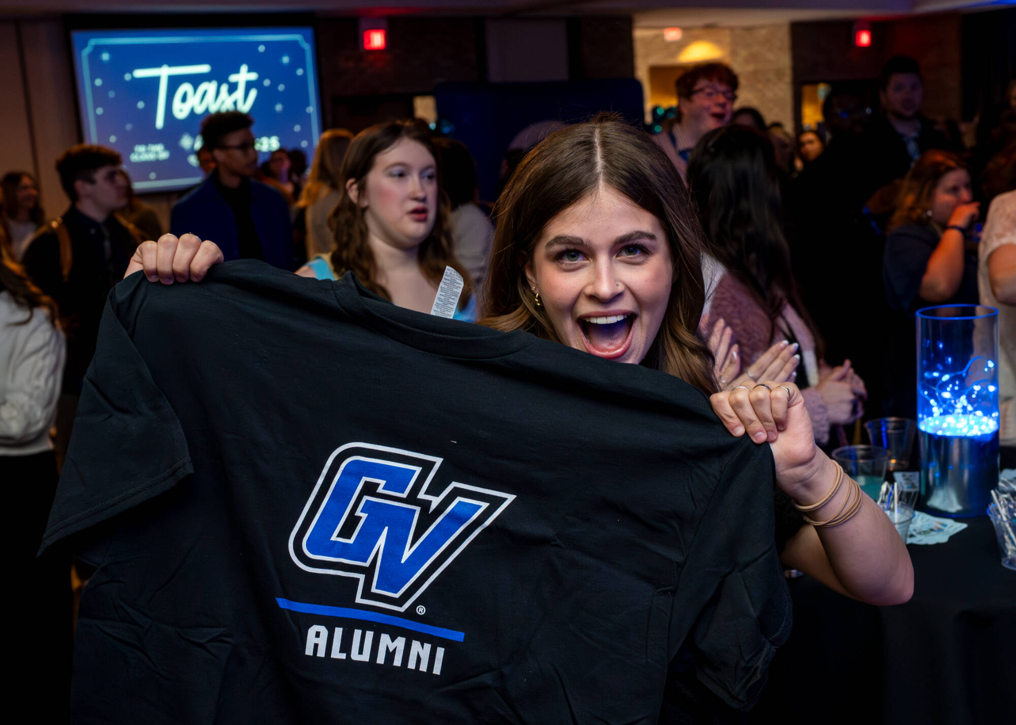 Woman holding up a GV Alumni shirt